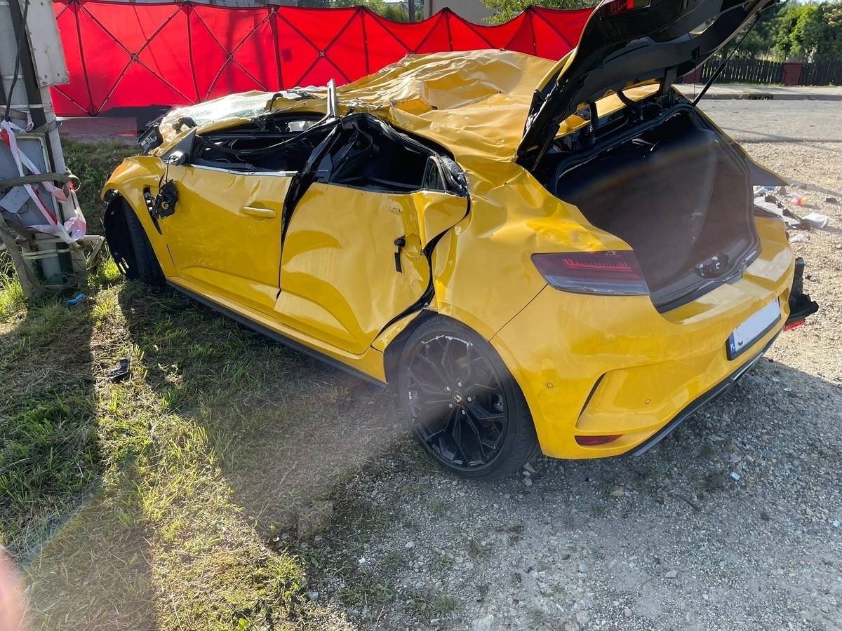 Zniszczony samochód marki Renault na miejscu wypadku w Harmężach, otoczony taśmami policyjnymi.