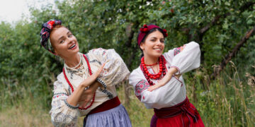 Dwie członkinie zespołu ludowego w tradycyjnych strojach, prezentujące folklor regionu