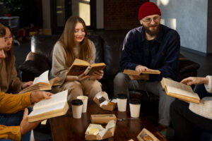Grupa młodych ludzi z książkami siedzących przy stole z kawą.